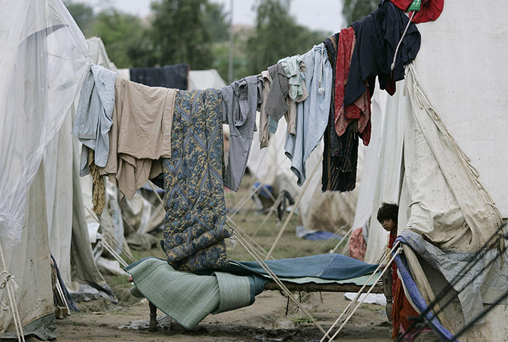Pakistan flood survivors: A young flood survivor looks out from a tent at a camp
