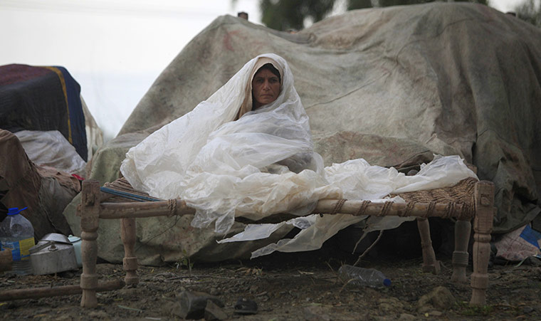 Pakistan flood survivors: A long-term Afghan refugee shields herself from rain