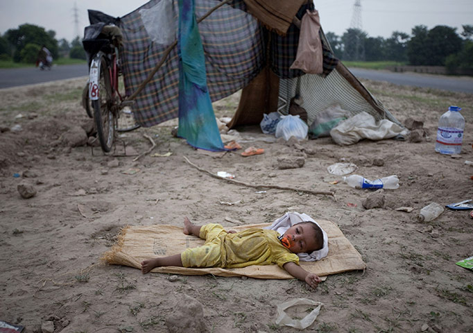 Pakistan flood survivors: A young flood victim sleeps next to a road after her family evacuated
