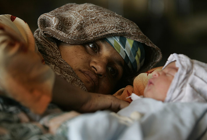 Pakistan flood survivors: A Pakistani woman looks at her day old baby at a camp 