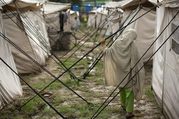 Pakistan flood survivors: A flood-affected girl walks outside her tent in the compound of a college