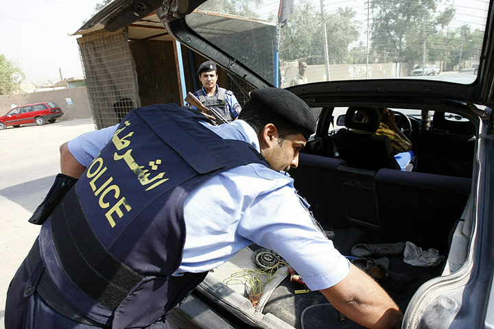 Baghdad bombing: An Iraqi police officer searches a car at a checkpoint in central Baghdad