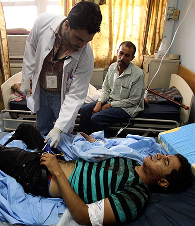 Baghdad bombing: A doctor checks a man who was wounded in a bomb attack in Baghdad