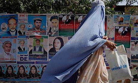 A woman walks past election posters in Jalalabad, Afghanistan