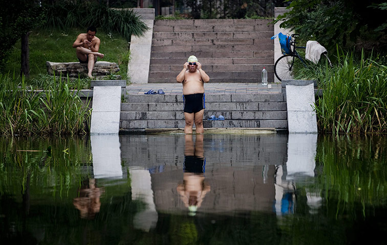 24 hours: Beijing, China: A man swims in a canal