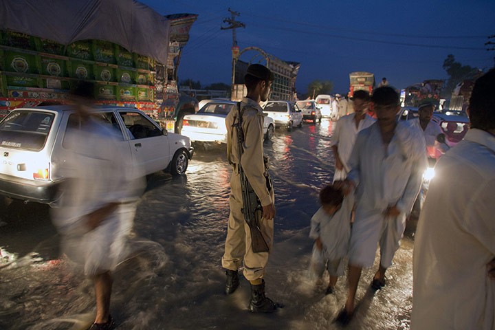 pakistan flooding: A paramilitary soldier stands to control the traffic 