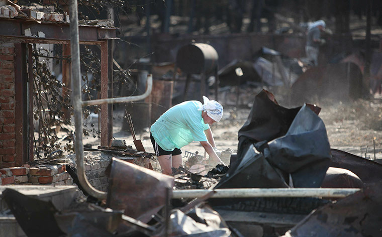 Forest fires in Russia: A woman inspects the remains of her burnt house at the edge of Voronezh