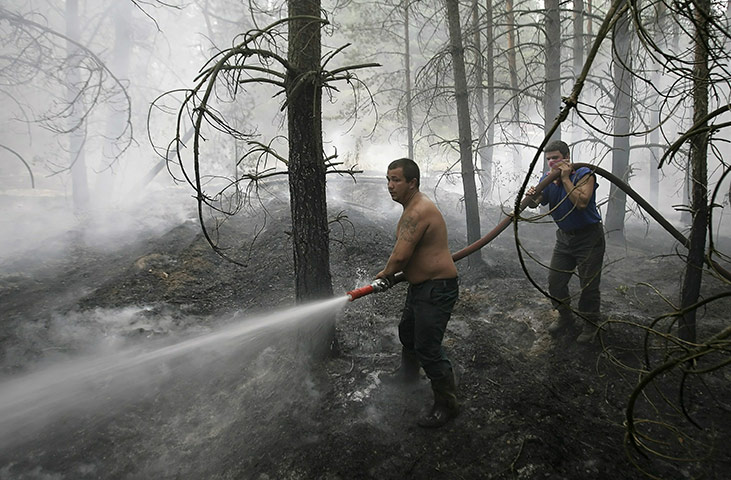 Forest fires in Russia: A firefighter douses flames in trees in the village of Lesnoye