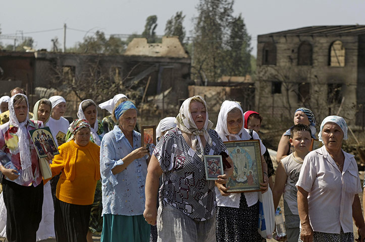 Forest fires in Russia: People carry icons during a religious procession in front of burnt houses