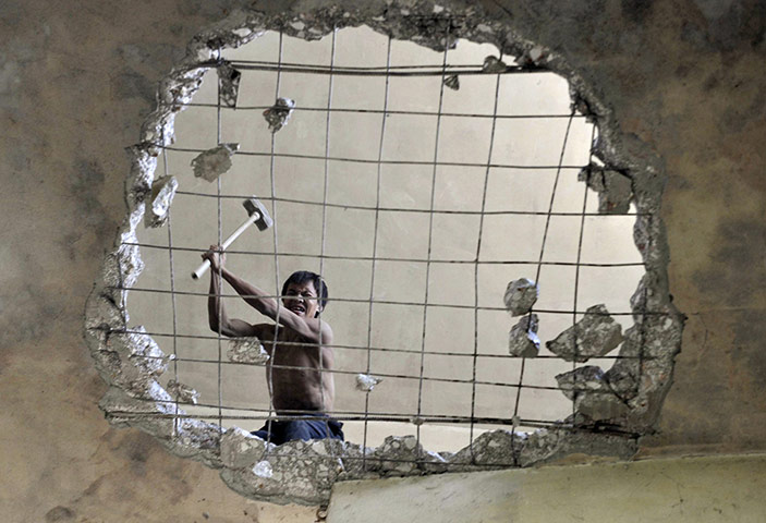 24 hours in pictures: A labourer demolishes a building in China