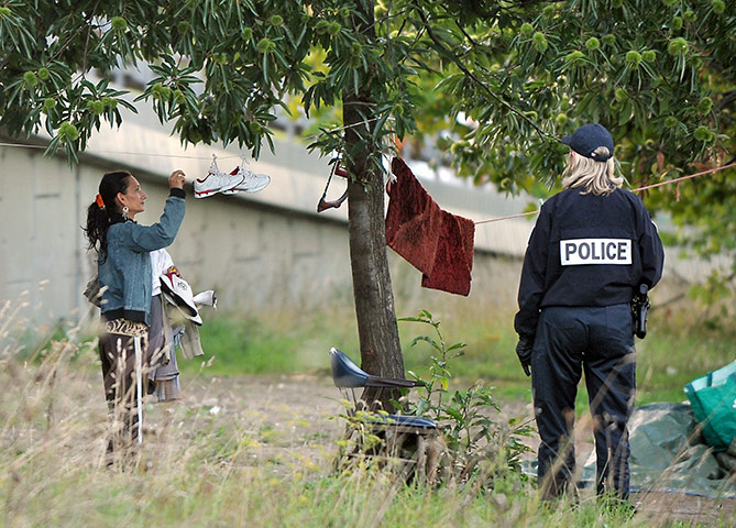 Roma deportation: A woman belonging to the Roma community takes shoes from a clothes line