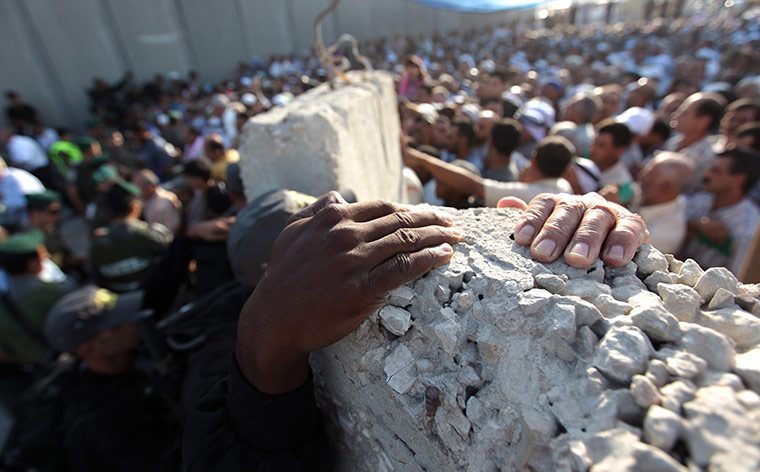 24 hours: Ramallah, West Bank: An Israeli policeman clutches onto the top of the wall
