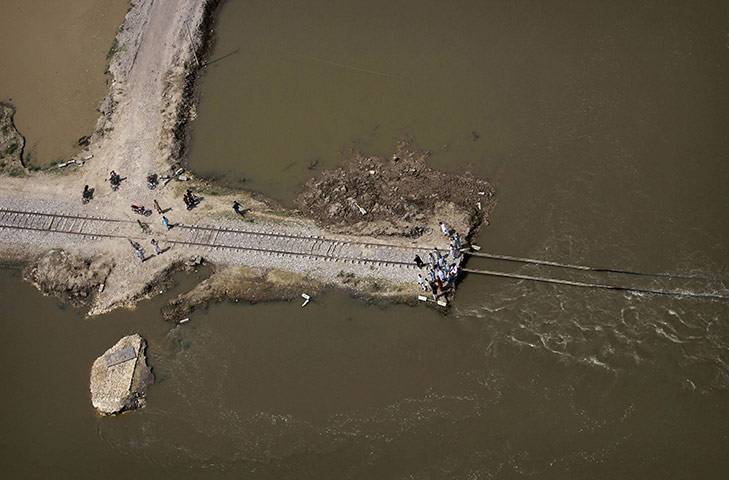 24 Hours: Pakistanis stand on a collapsed railway line in a heavily flooded area 