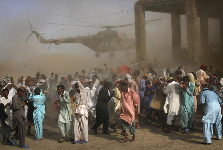 24 Hours: Pakistanis crowd around an army helicopter as it lands during a food drop