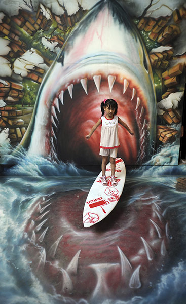 24 Hours: A girl poses between a mock shark's teeth made by graffiti artists