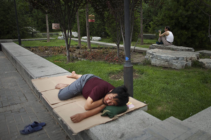 24 hours in pictures: Beijing, China: A man smokes after hanging his bird cages on a tree
