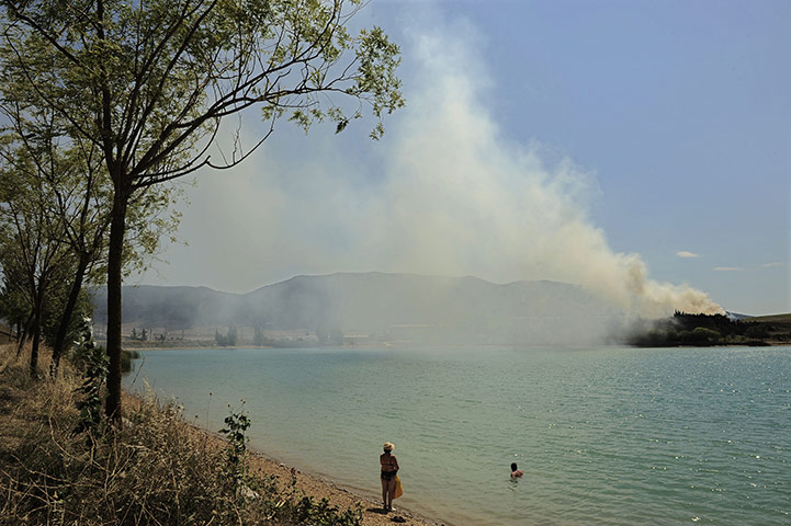 24 hours in pictures: forest fire burning on the side of a mountain above La Morea Lake, Spain 