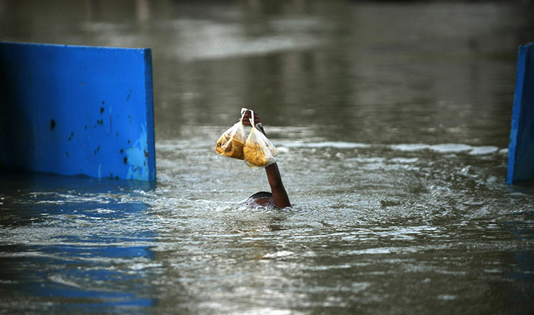 Pakistan Flood Update: A Pakistani boy swims as he tries to keep his food dry