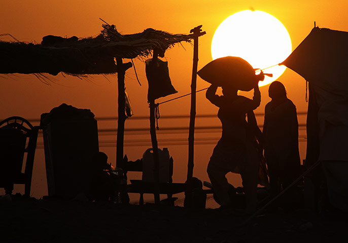 Pakistan Flood Update: A Pakistani woman carries relief goods as the sun sets