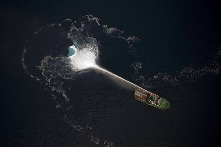 24 hours in pictures: Greenland: A ship melts an iceberg by spraying it with seawater