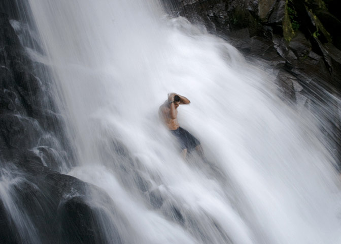 A man sit in the middle of the waterfall before diving in