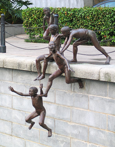 cheerful bronze of boys jumping off the harbour wall
