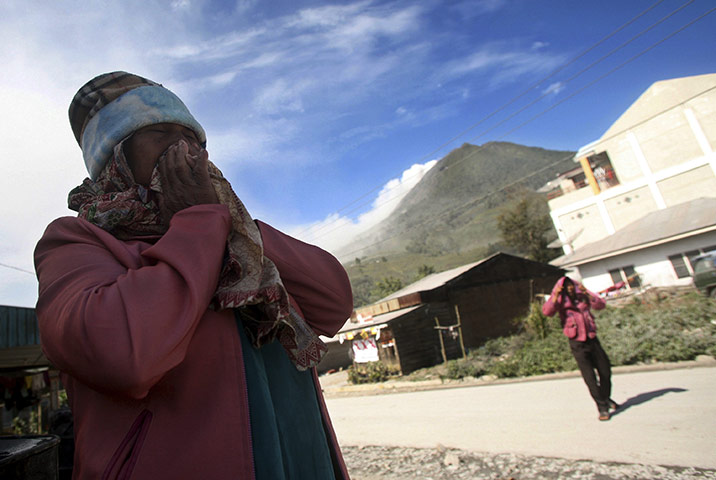 24 hours: Karo, Indonesia: A villager covers her nose and mouth from volcanic ash