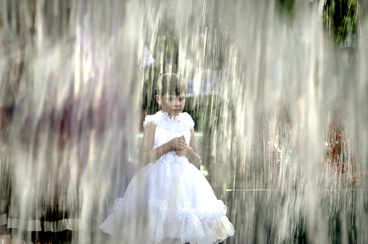 24 hours: Bucharest, Romania: A girl stands by a fountain during a heatwave