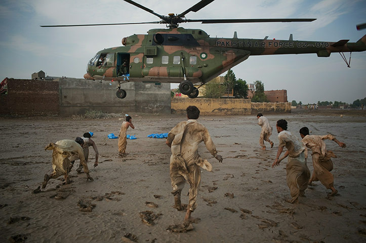Floods in Pakistan: Local residents scramble to recover water bottles dropped from a helicopter