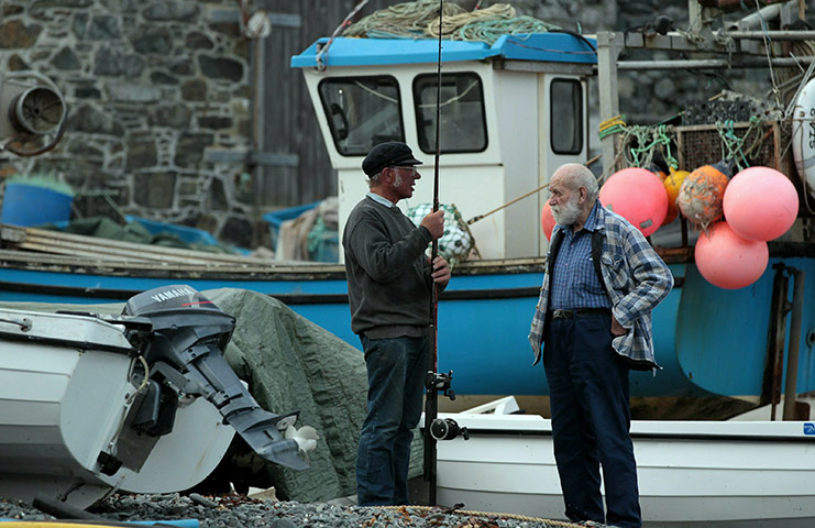 Helston fishing: A fisherman chats beside the fishing boats in Cadgwith cove 