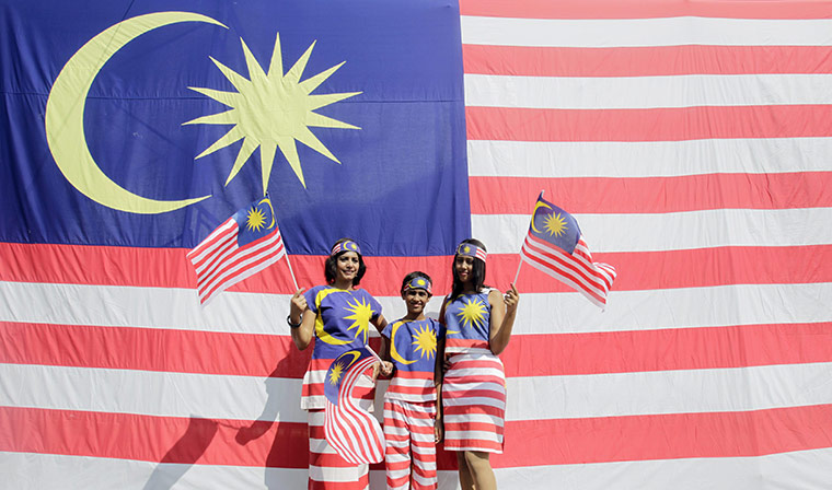Malaysian Independence: People pose in front of a national flag during celebrations in Kuala Lumpur