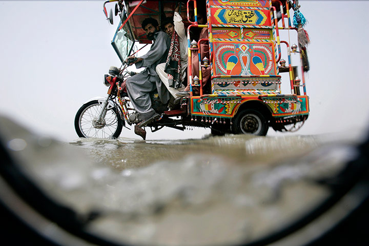 24 hours in pics: A Pakistani crosses a flooded area using a motorcycle
