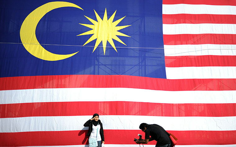 24 hours in pics: A Malaysian girl poses for a picture in front of a national flag