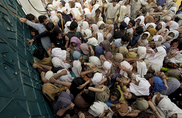 Pakistan flood : Flood-stricken Pakistanis wait outside a relief centre