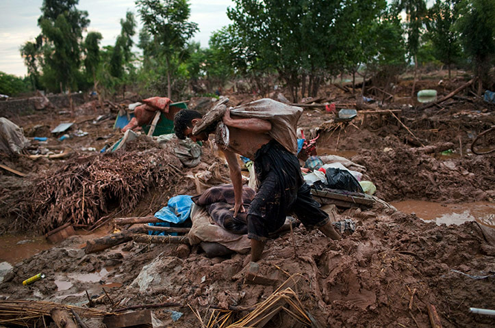 Pakistan flood : A man carries belongings recovered from his flood destroyed home