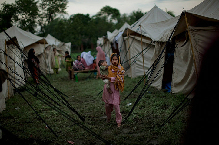 Pakistan flood : A girl holds a baby at a relief camp in Nowshera