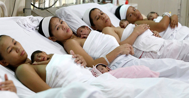Filipino mothers tuck their babies on their chests at hospital in Manila