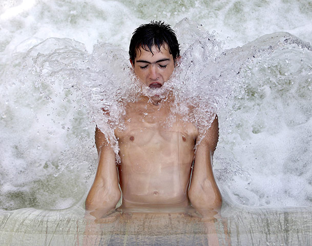 24 hours in pictures: A Romanian young man cools off in the fast flowing waters at a dam