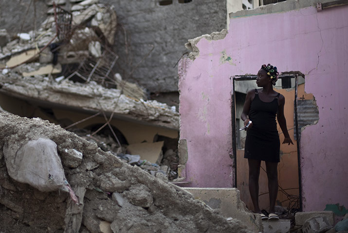 24 hours in pictures: Port-au-Prince, Haiti: A woman stands on the remains of her home