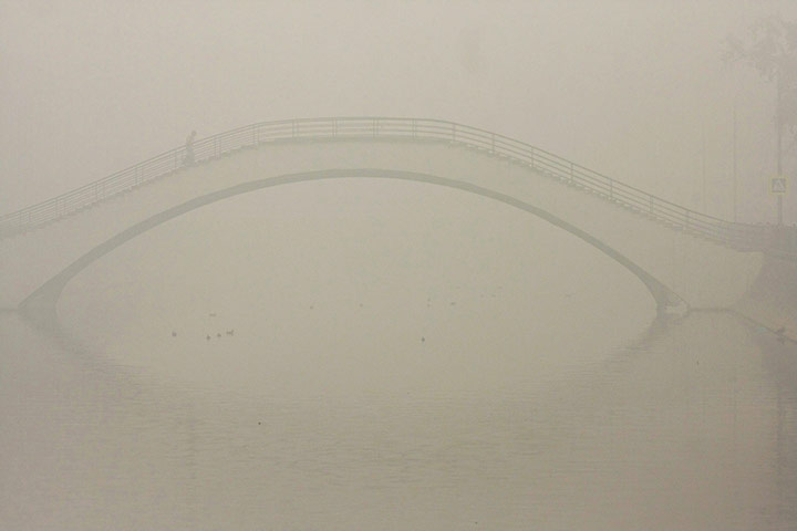 Russian Fires: A Muscovite crosses a pedestrian bridge in the heavy smog in Moscow