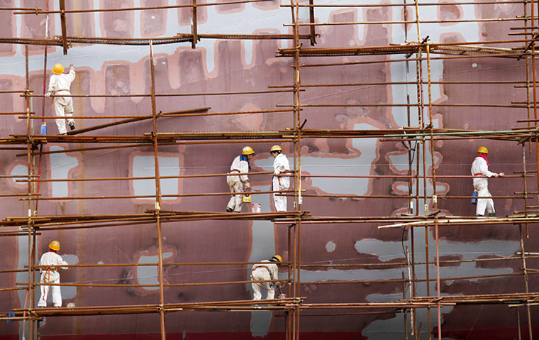 24 hours in pictures: Workers standing on scaffoldings paint a ship at a shipyard in Nanjing