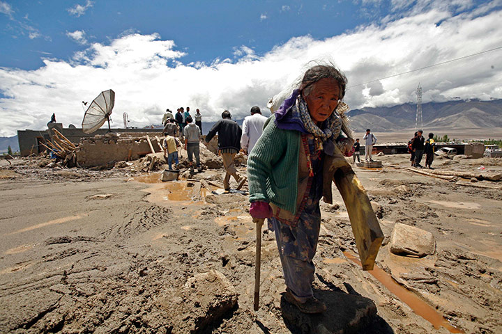 Leh flash floods: A local resident carries her belongings from Choglamsar village