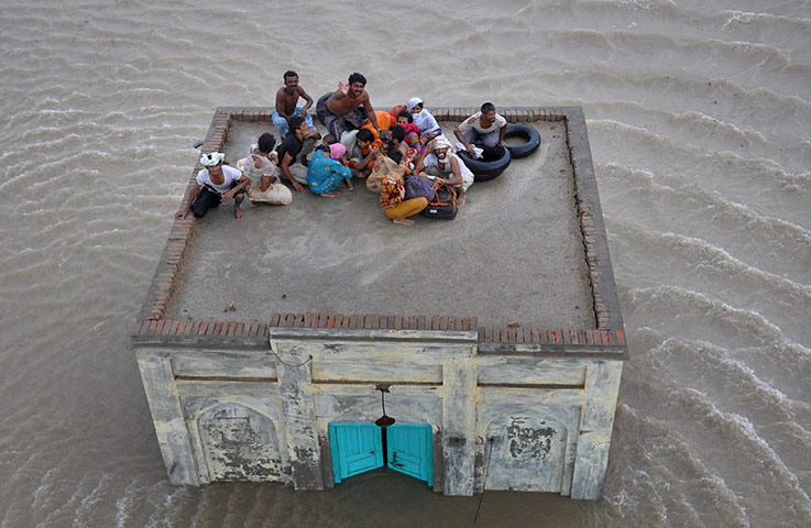 Pakistan update: A family takes refuge on top of a mosque while awaiting rescue from flood