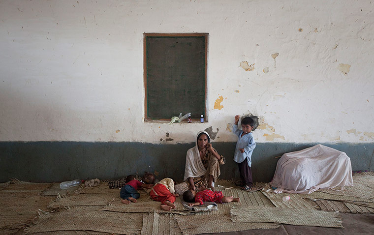 Pakistan update: A flood victim takes refuge with her four children in a train station