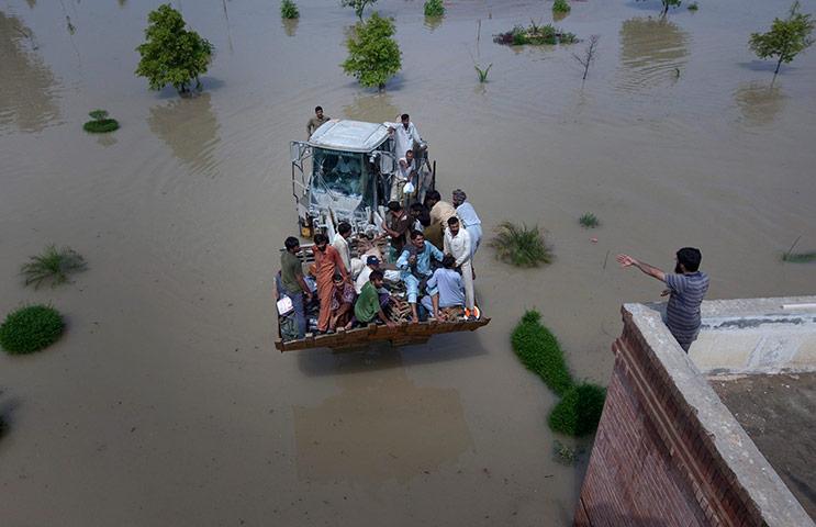 Pakistan aerial: A bulldozer carries flood victims to a near by rooftop in Muzaffargarh