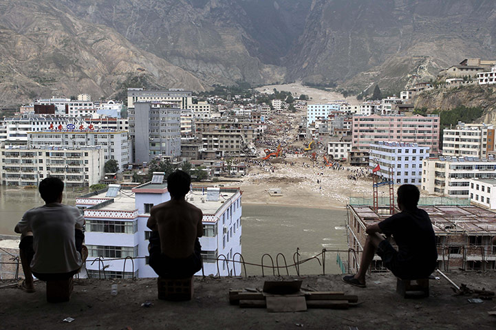 China Flood update: Workers at a construction site watch search for mudslide survivors in China
