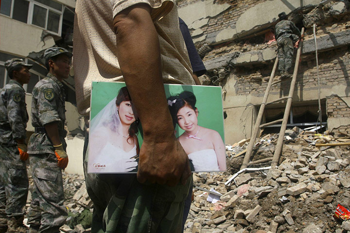 China Flood update: A man holds a family photo, China mudslide floods rescue operation