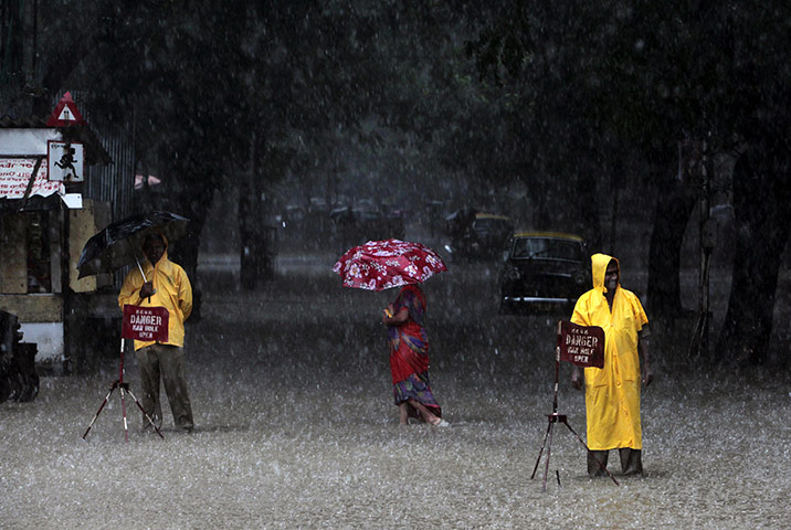 24 hours: Mumbai, India: Civic officials guarding manholes on a flooded street 