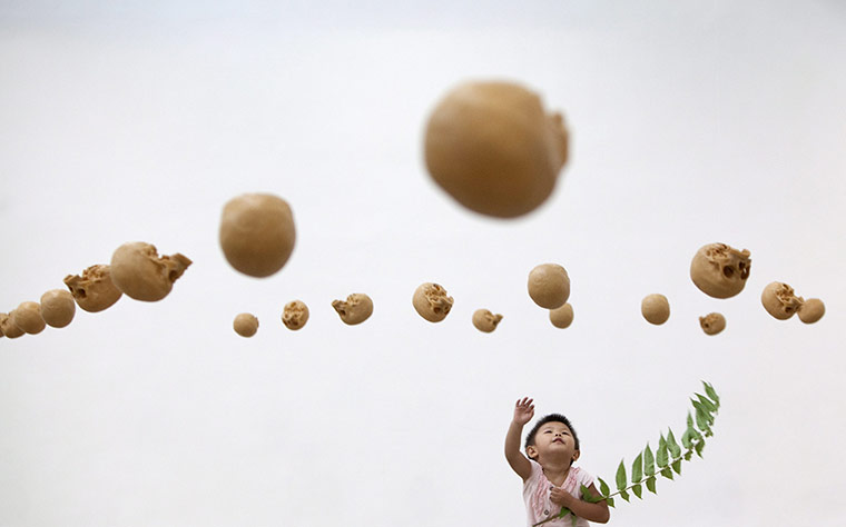 24 hours: Beijing, China: A boy looks at sculptures of skulls