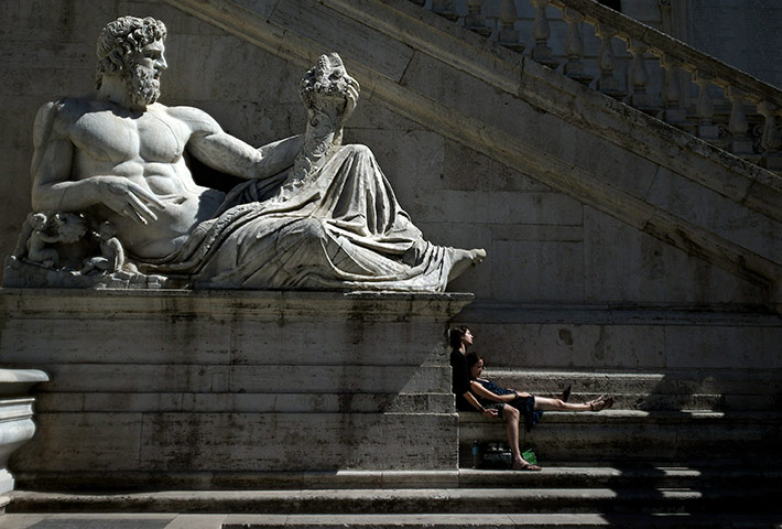 24 hours: Rome, Italy: Tourists sunbathe by the statue of the River God Tiber 